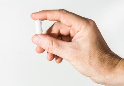 Man holding white pill in his hand