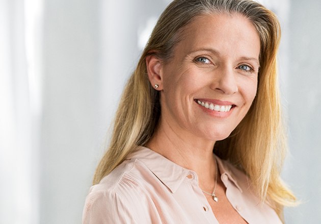 An older woman wearing a beige blouse and smiling after having her small cracks fixed with direct bonding