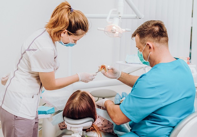 A patient listening closely as a dentist and dental assistant explain how direct bonding works