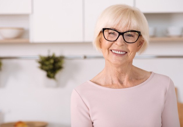 Senior woman with glasses smiling in kitchen