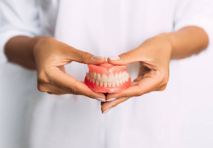 A closeup of dentures held by a dentist