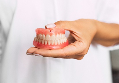 dentist holding dentures in hand 