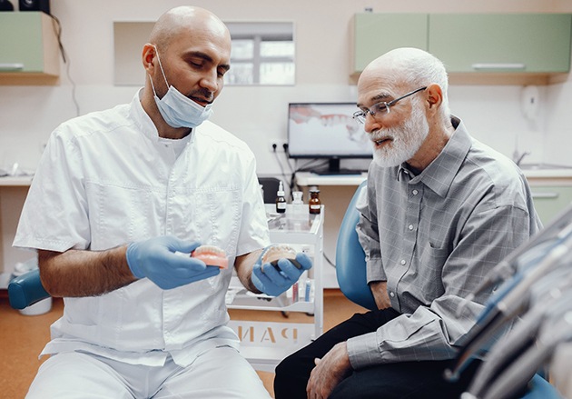 Dentist talking to man about cost of dentures in Plainview