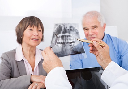 Dentist showing older couple dental X-ray 