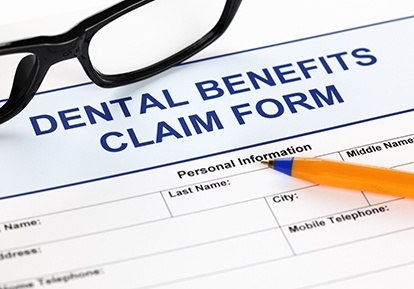 Dental insurance paperwork with pen and glasses