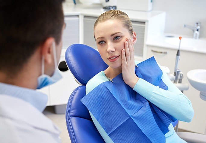 girl holding cheek talking to dentist