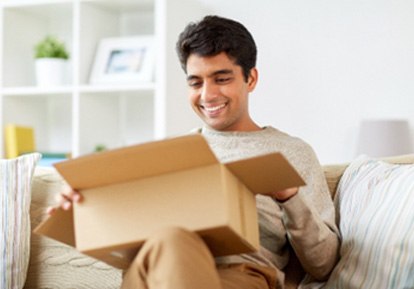 Smiling man sitting on couch and opening box
