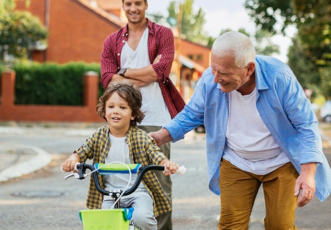 man helping his grandson ride a bike