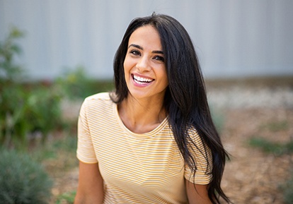 Woman in yellow shirt smiling outside