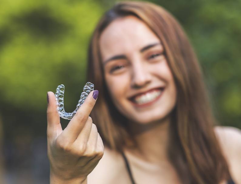 girl holding out clear aligner