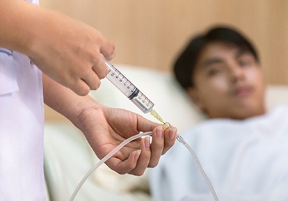 A doctor injecting medicine into a patients I V tube