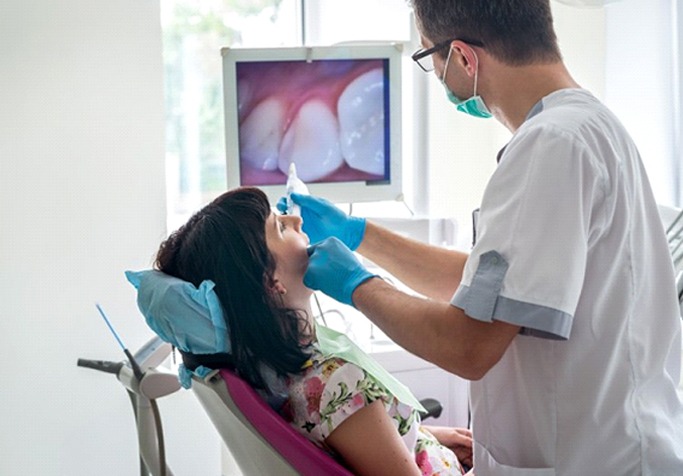 dentist using an intraoral camera to examine a patient’s mouth