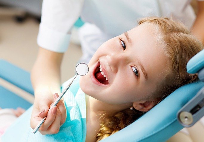 young girl in exam chair smiling at camera