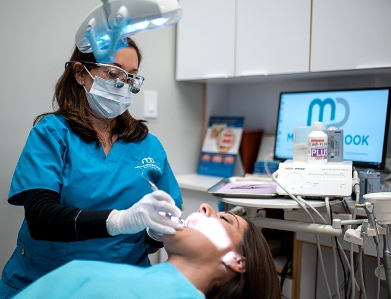 Dental team member giving a woman a dental cleaning
