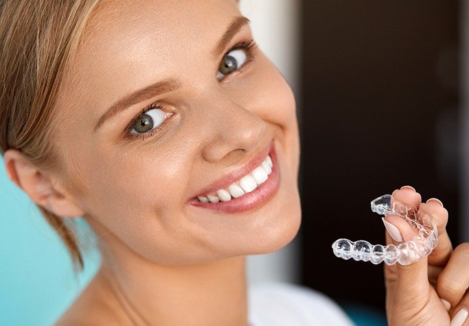 blonde girl smiling with invisalign tray
