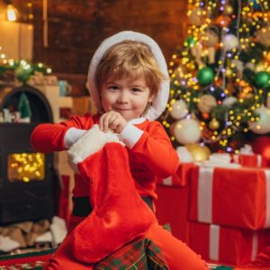 little kid pulling stocking stuffers out of their red stocking 