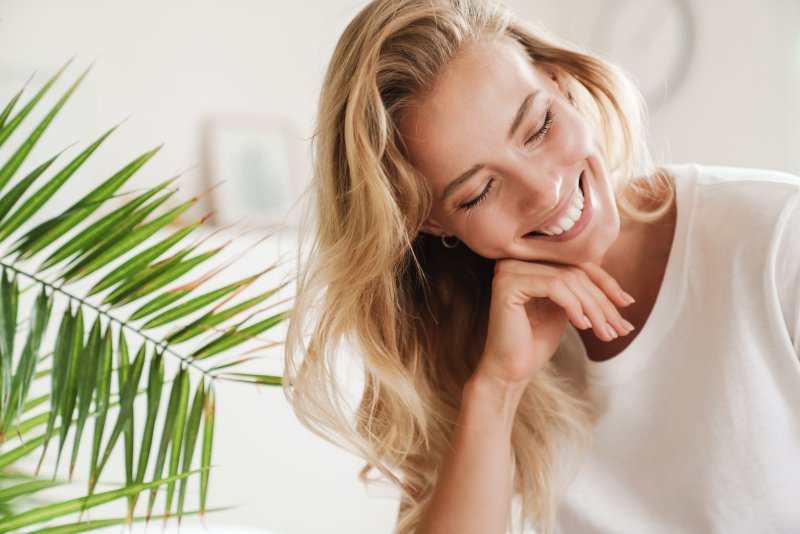 a young woman smiles widely with her eyes closed and head tilted 