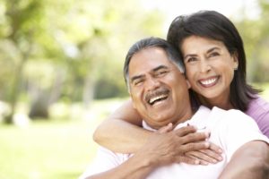 Couple with dental implants in Plainview laughing outside