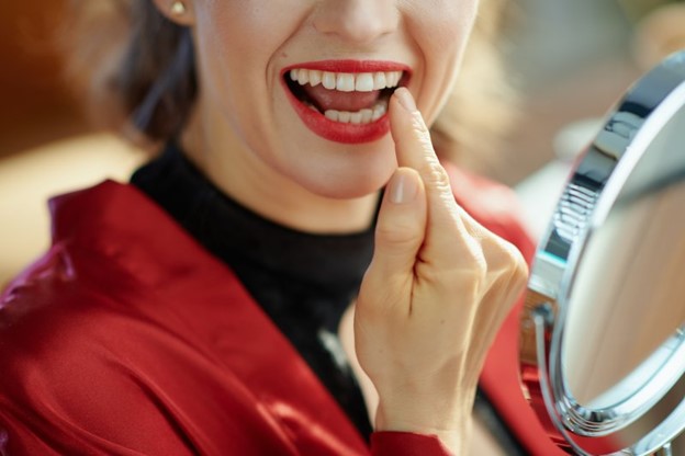 Woman inspecting her teeth in a mirror.