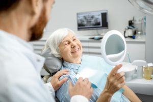 Older woman admiring her smile at the dentist’s office.
