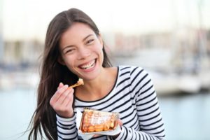 a woman smiling and eating waffles on International Waffles Day