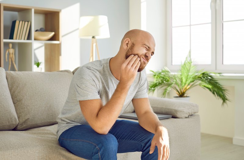 A man rubbing his jaw as the pain from dry socket spreads