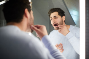 Man examining his loose tooth in a mirror